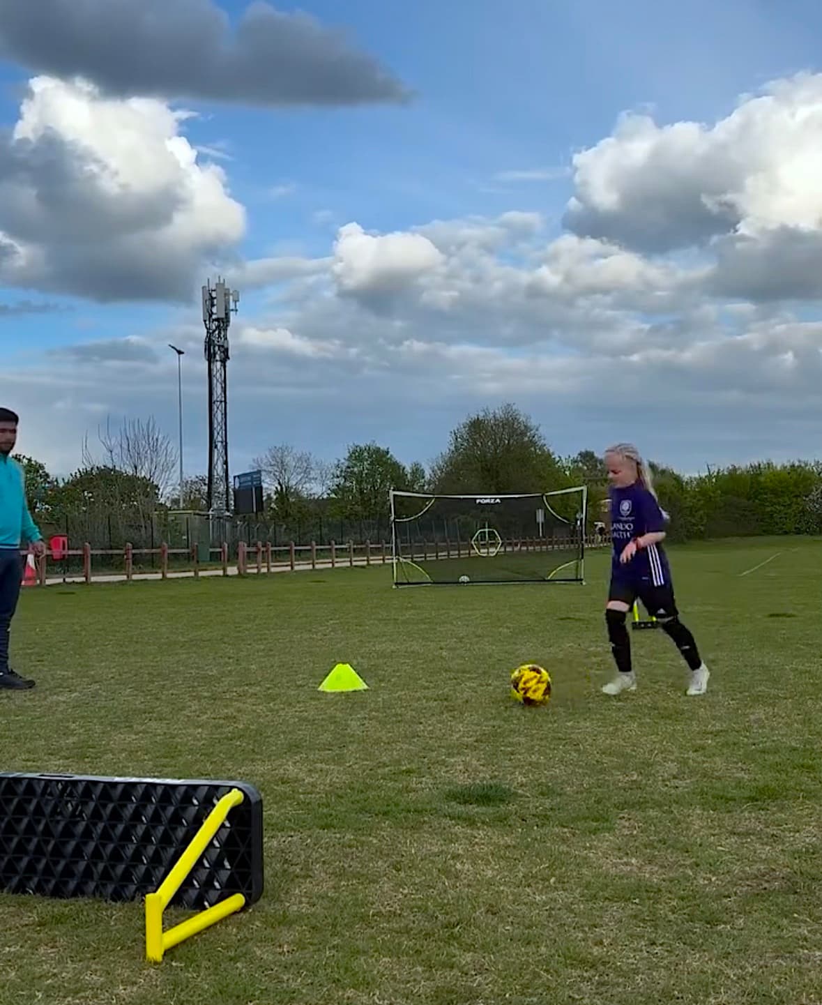 Young footballer training on the pitch with coach